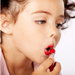 Photo of young girl applying lipstick