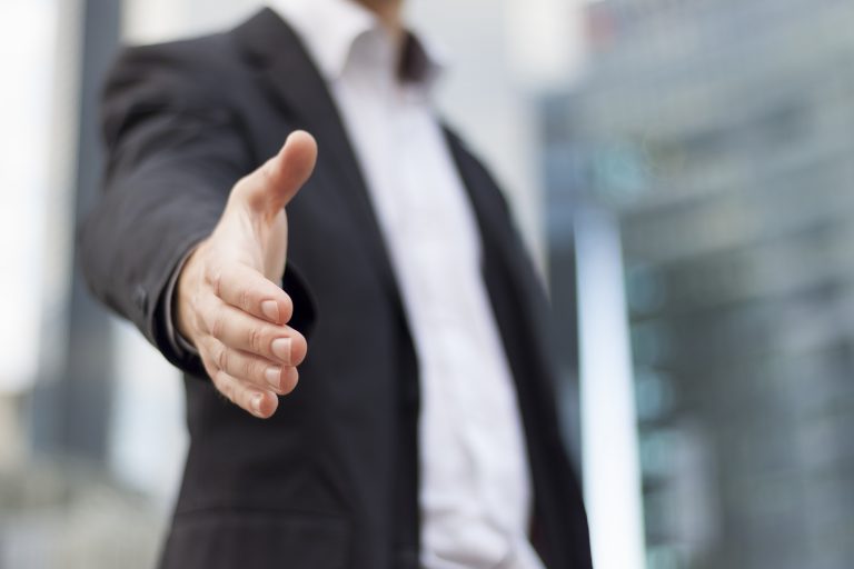 A faceless person holds their hand out for a handshake.
