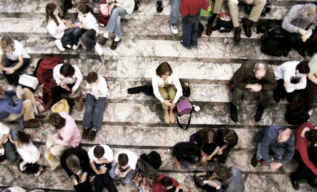 Woman sitting alone in the middle of a crowd