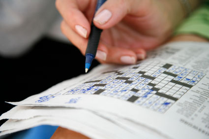 This is a photo of an individual completing a crossword puzzle in pen. 
