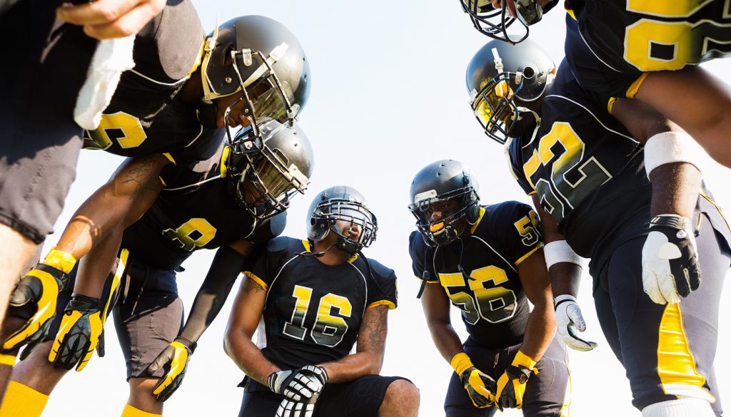 Football team huddled during time out while playing game