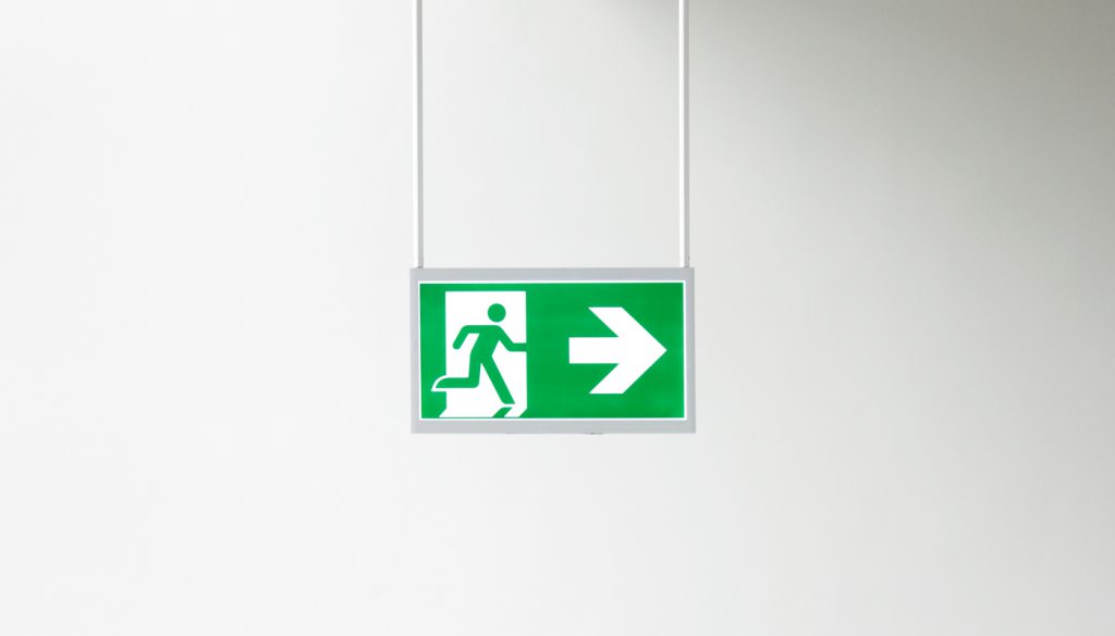 Closeup of modern illuminated emergency exit sign .