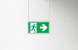 Closeup of modern illuminated emergency exit sign .