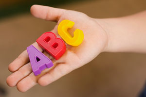This is a photo of a child holding blocks shaped like letters of the alphabet.