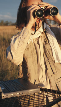 This is a photo of a person in a field holding a pair of binoculars.
