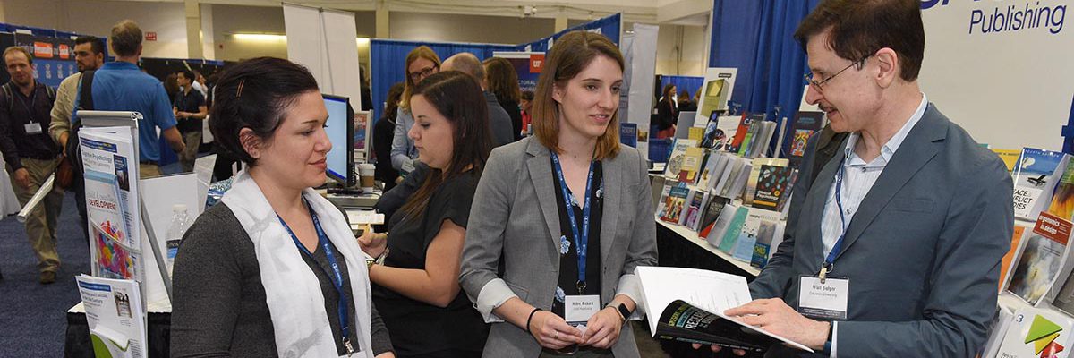 APS Exhibitor chatting with attendees at exhibit booth.