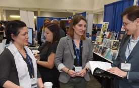 APS Exhibitor chatting with attendees at exhibit booth.