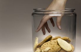 Woman reaching for cookies in cookie jar, close-up of hand