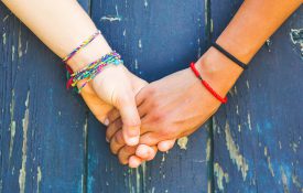 Teens holding hands with a wooden background.