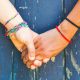 Teens holding hands with a wooden background.