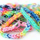 Photo showing a pile of rainbow coloured loom bracelets, made from coloured rubber loom bands. These friendship bracelets are popular with young children, who weave the rubber bands together using a simple plastic loom device.