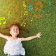 Little girl smiling and lying on grass with music notes around her