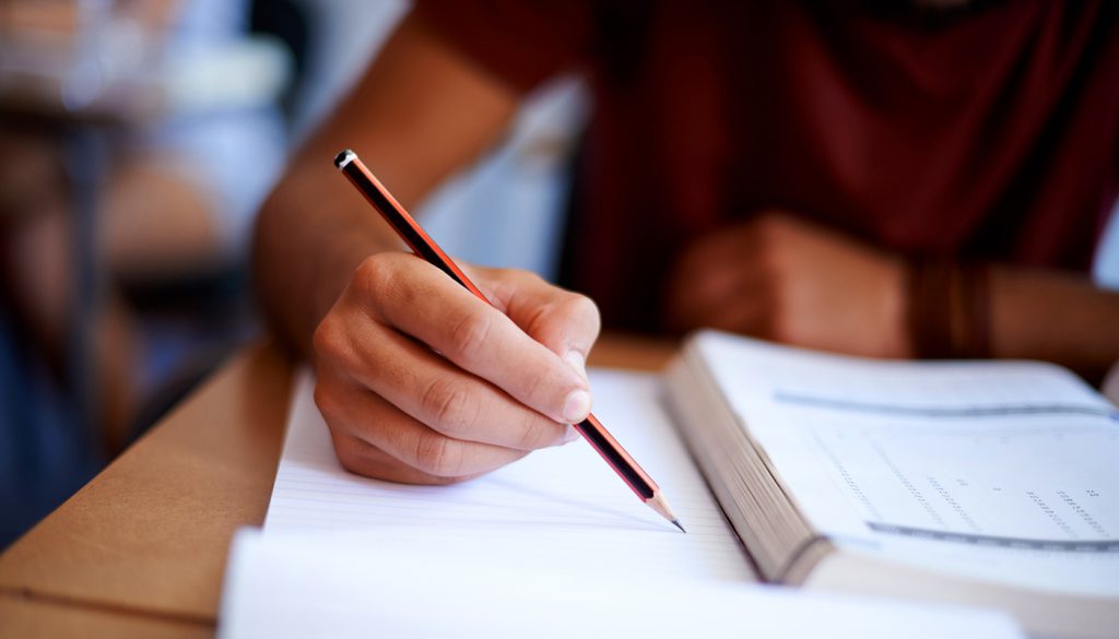 Closeup shot of a young man writing on a note pad