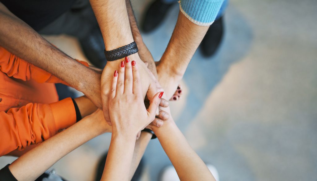 Multiethnic group of young people putting their hands on top of each other. Close up image of young students making a stack of hands.