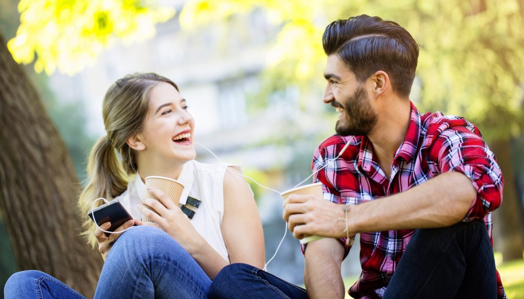 Young woman and young man, sharing headphones and smiling