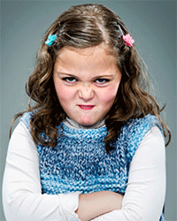 This is a photo of a child who is crossing her arms and making an aggressive face.