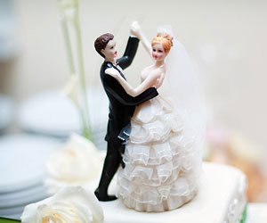 This is a picture of a wedding cake with bride and groom figurines.