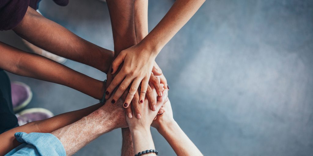 Close up top view of young people putting their hands together. Friends with stack of hands showing unity.