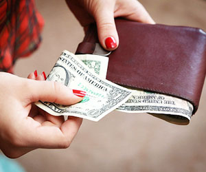 This is a photo of a woman taking cash out of her wallet.