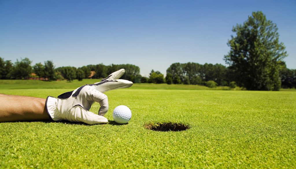 Golfer tipping golf ball into the hole