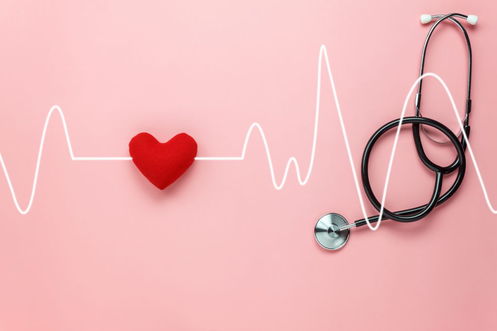 Aerial view of pink tabletop with a sewed heart and stethoscope