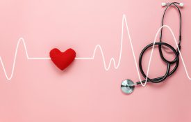 Aerial view of pink tabletop with a sewed heart and stethoscope