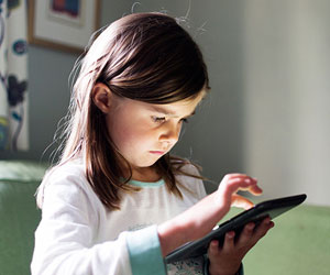 This is a photo of a young girl using a tablet.