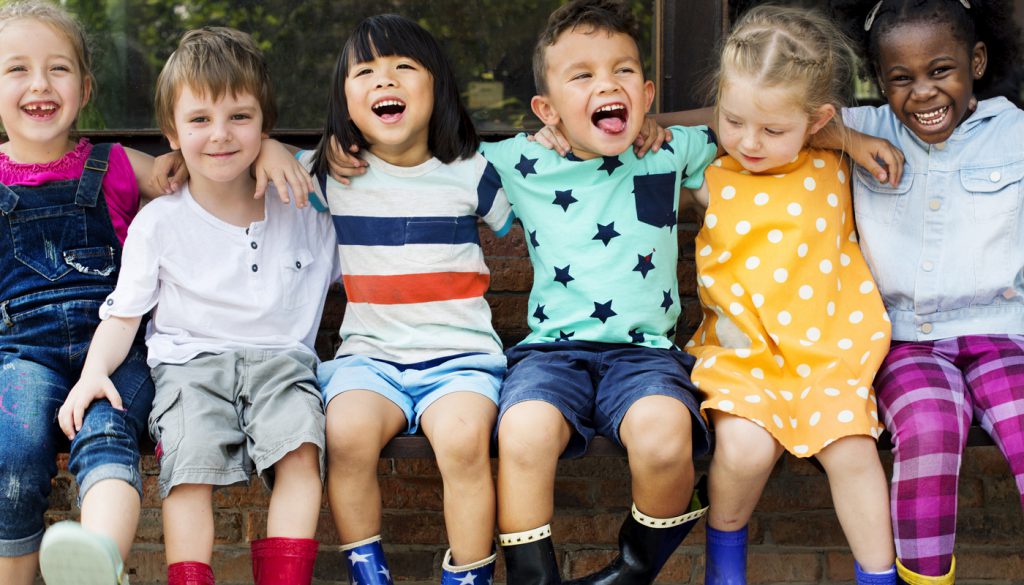 Group of kindergarten kids friends arm around sitting and smiling fun