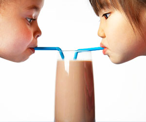 This is a photo of two girls sharing a milkshake.