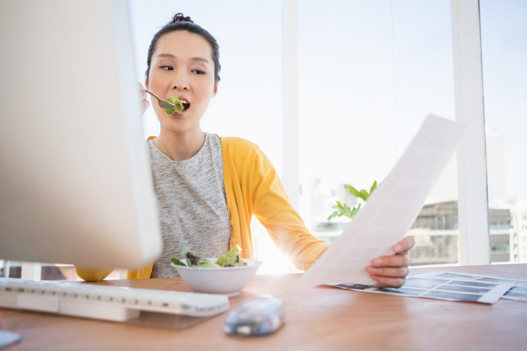 Businesswoman eating a salad while working