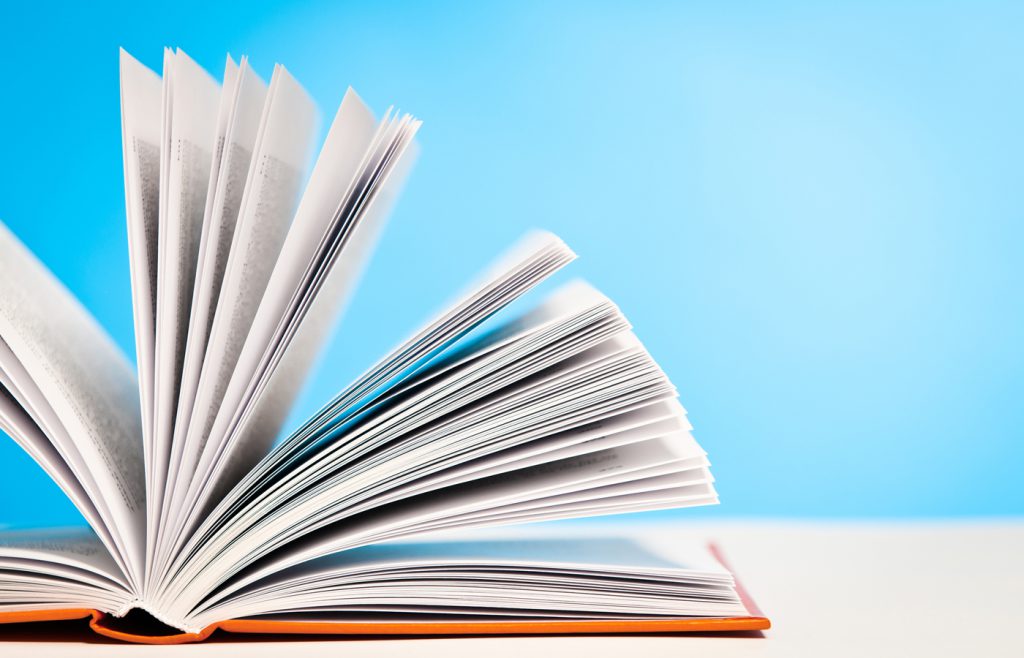 This is a photo of an open book on desk against a blue background