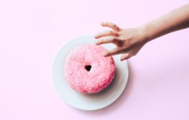 Child reaching for a pink donut with sprinkles