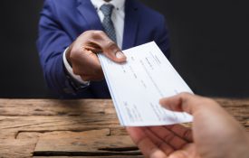 Businessperson hand passing over a check to another hand across a table