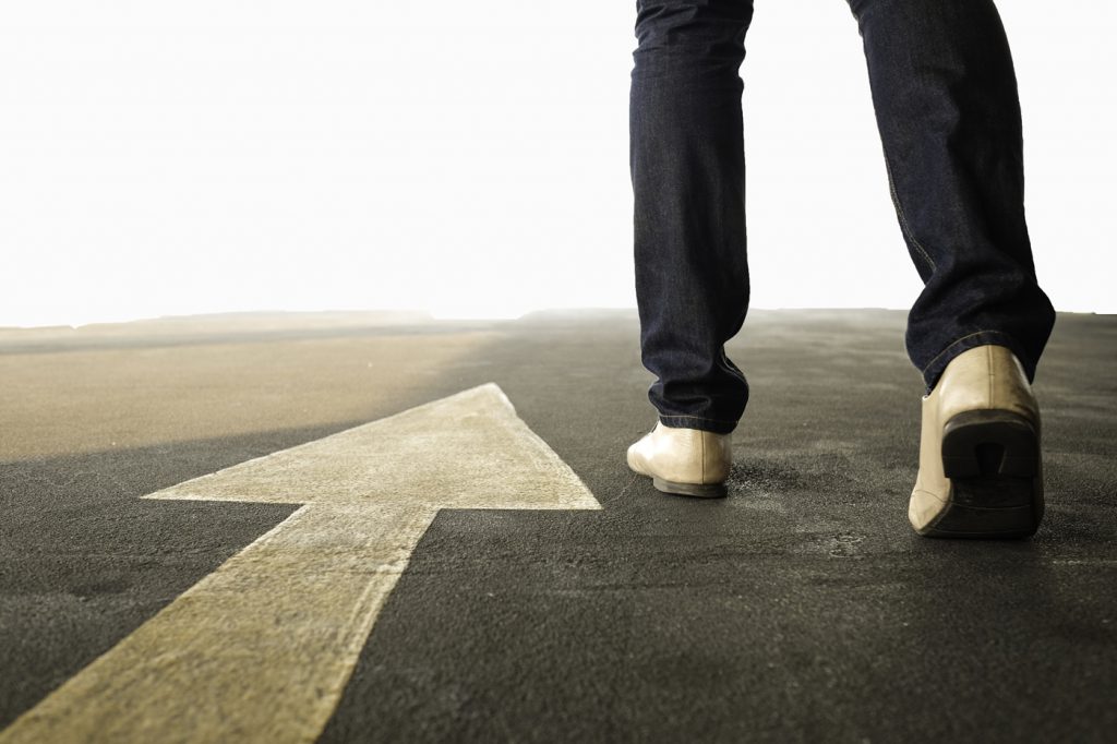 Person walking in the direction of an arrow pointing ahead