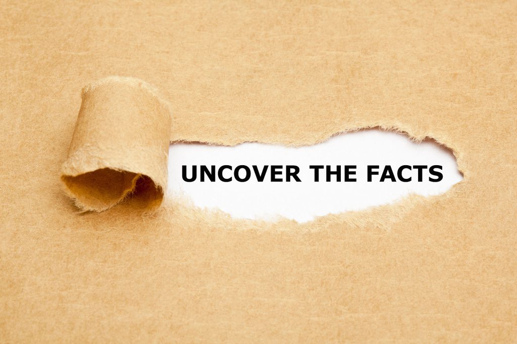 A photo of paper torn back to reveal the phrase "uncover the facts"