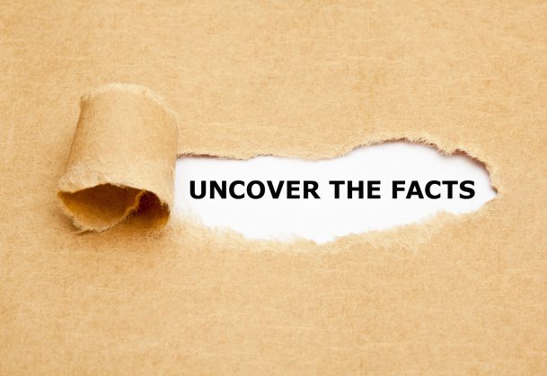 This is a photo of a piece of paper torn to reveal the phrase "uncover the facts"