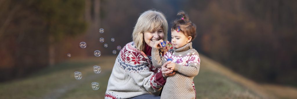 Grandmother and granddaughter blowing bubbles