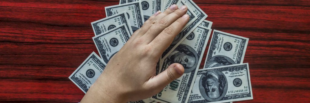 Hands grabbing money from a desk