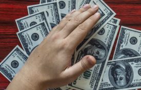 Hands grabbing money from a desk