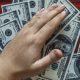 Hands grabbing money from a desk