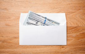 Top view of blank envelope with dollar banknotes on wooden desktop.