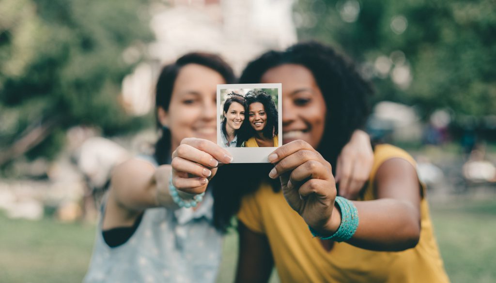 Friends holding a Polaroid photo they took of themselves
