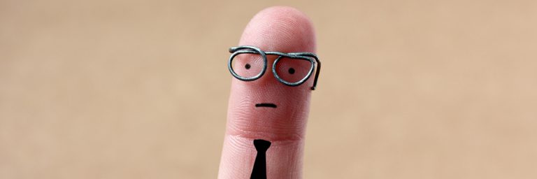 This is a photo of a pinky fingerwith drawn face, glasses, and tie.