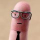 This is a photo of a pinky fingerwith drawn face, glasses, and tie.
