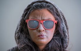This is a photo of a woman wearing hood and sunglasses with frost on her face.