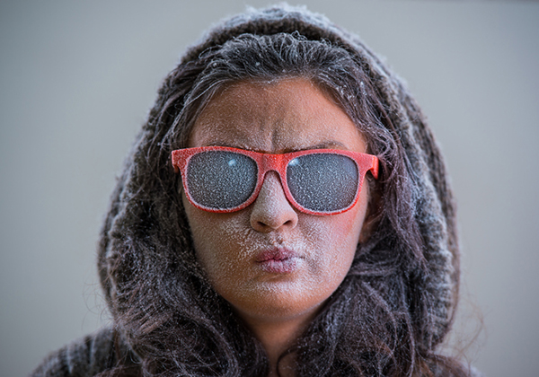 This is a photo of a woman wearing hood and sunglasses with frost on her face.