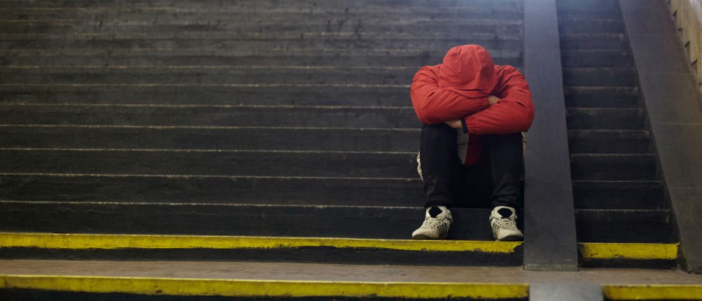 This is a photo of a teen sitting alone on a set of stairs.