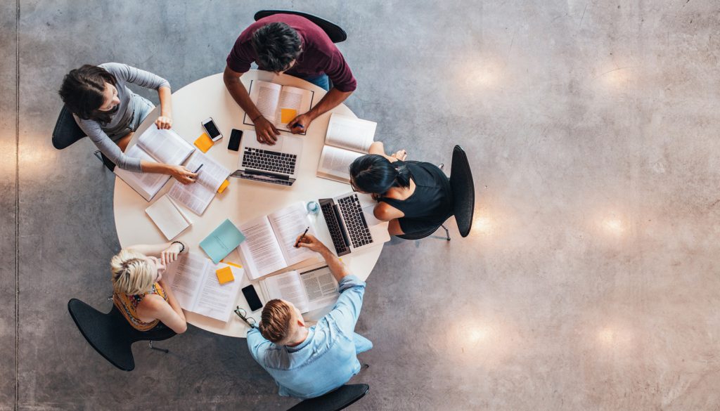 This photo shows a top view of group of students studying together at table.