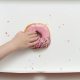 Overhead view of a doughnut box with a young girl's hand reaching to grab the last pink strawberry frosted donut.