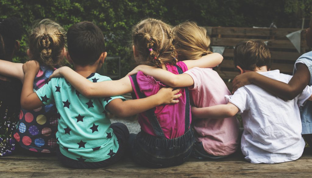 Group of kindergarten kids friends arm around sitting together